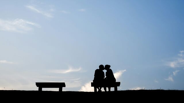 silhouette of 2 person sitting on bench during sunset